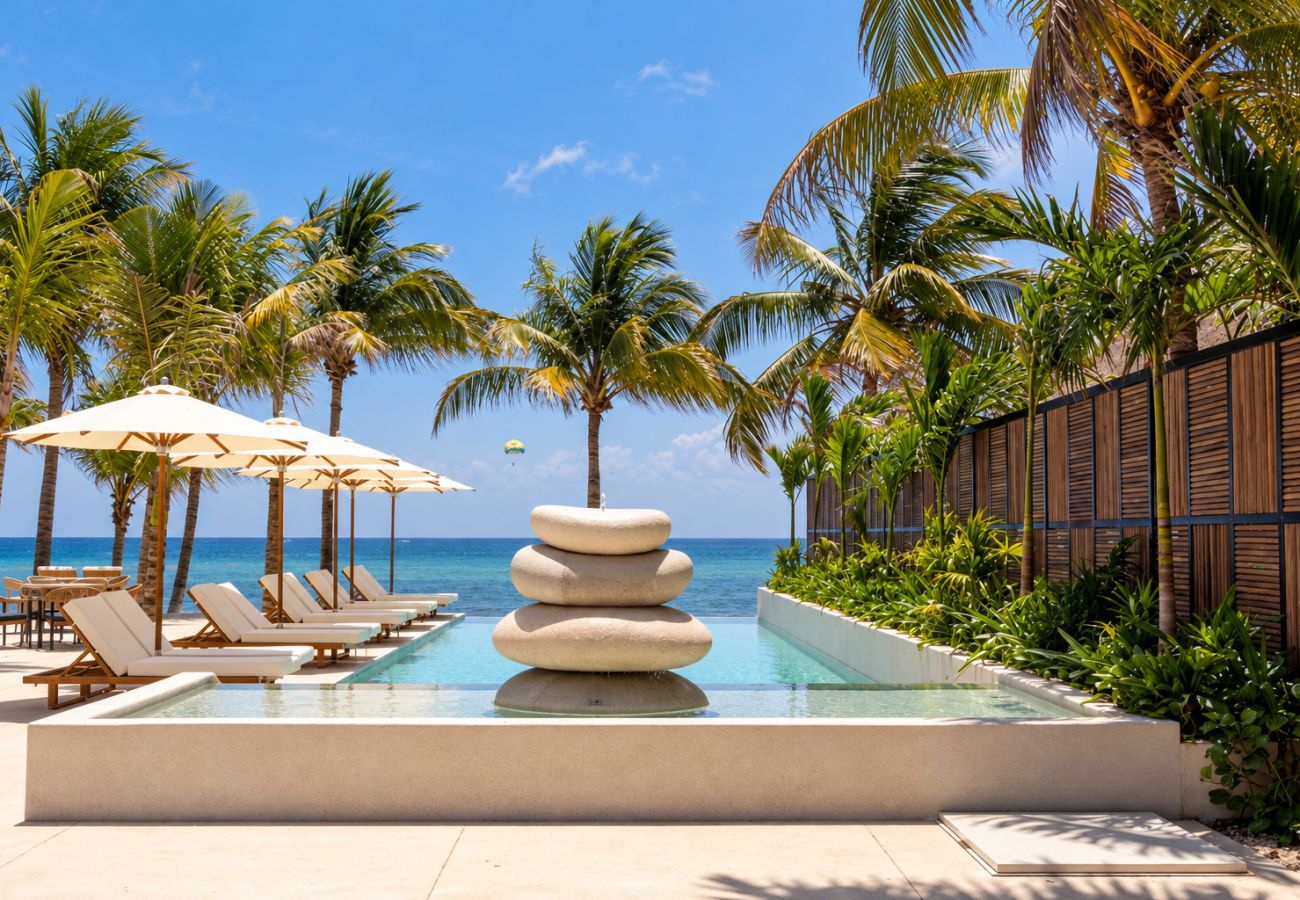 Club de playa con tumbonas, sombrillas y palmeras frente al mar Caribe en Playa del Carmen.